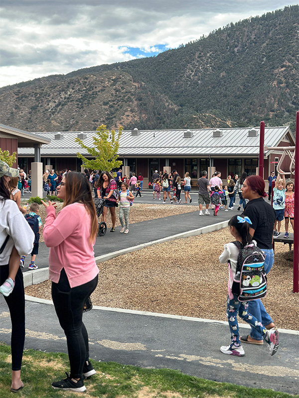 Parents, students, and staff enjoying time together before the bell rings outside of school campus on first day of school